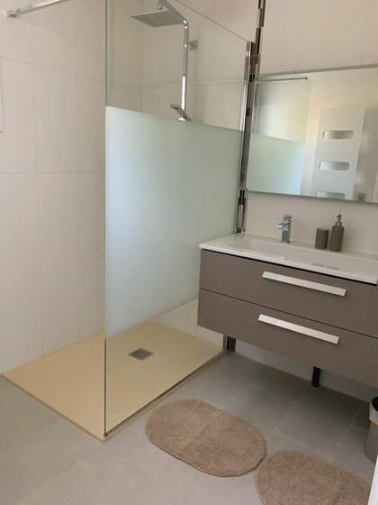 Salle de bain équipée d’une douche à l’italienne et d’un meuble vasque moderne.